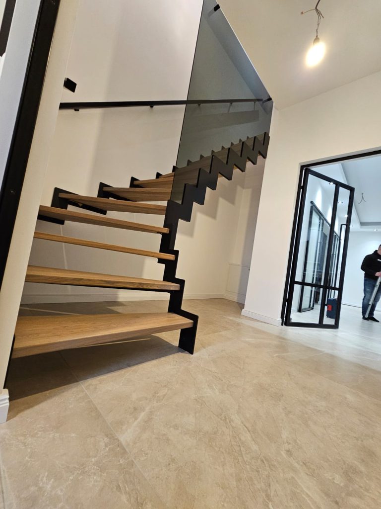 W-49 Stahlwangentreppe in Schwarz Zick-Zack, ¼ gewendelt, Stufen aus Eiche AB, Graphitglas