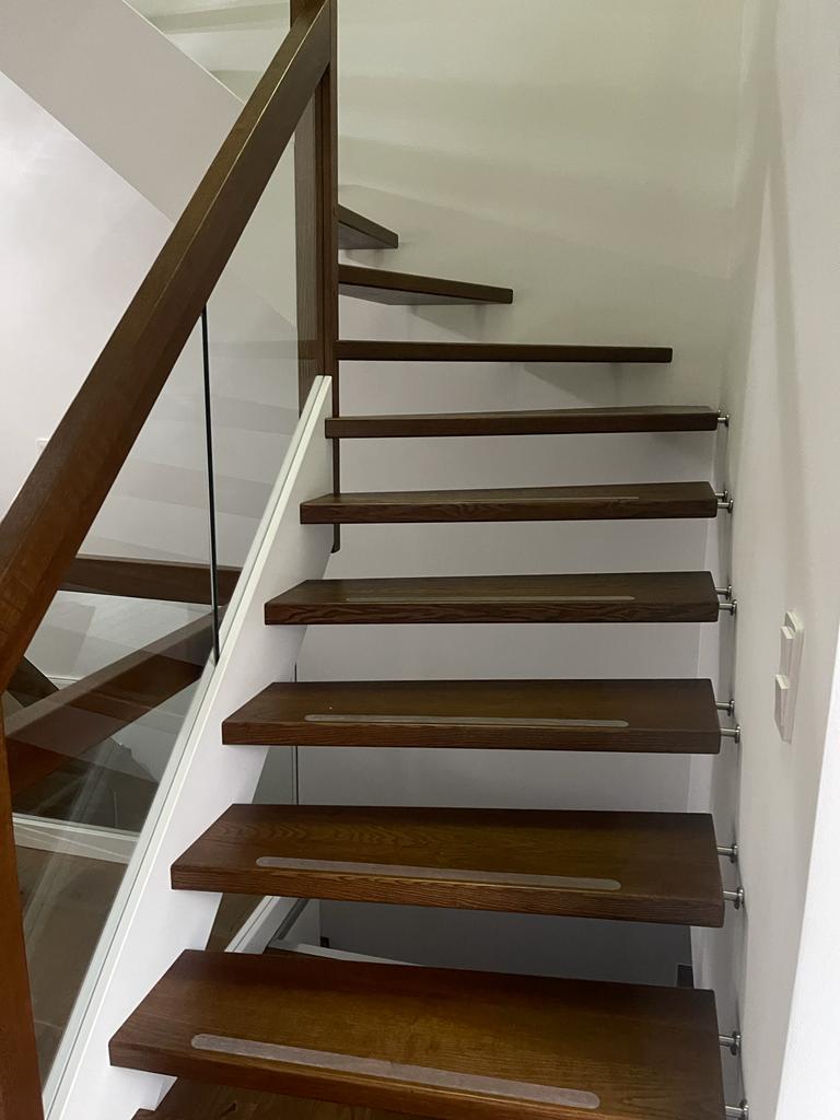 W-26 Holzwangentreppe, ¼ gewendelt, Stufen aus Esche gebeizt, Glasgeländer, Klarglas, Wangen in Weiß