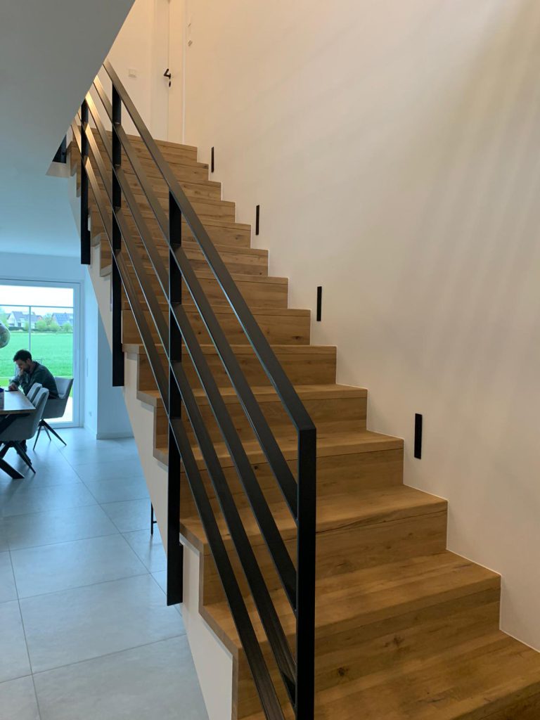 B-4 Holztreppe auf Betontreppe, Gerade, Ganze Treppe aus Eiche rustikal, Stahlgeländer in Schwarz, Tisch